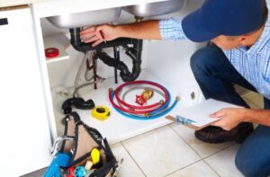 Plumber cleaning a drain under a sink.