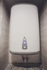 Instant tankless electric water heater installed on white tile wall with input and output pipe outlet and elcb safety breaker system